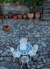 Fototapeta na wymiar Elegant white table and chairs stand on a stone terrace in Greece