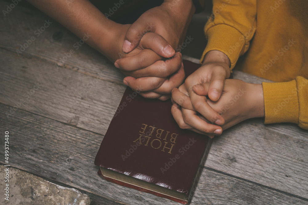 Wall mural Close-up two christian read bible. Hands folded in prayer on a Holy Bible on wooden table. online group worship, World Day of Prayer, international day of prayer, hope, gratitude, thankful, trust - Wall murals