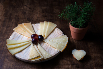 Spanish cheese board next to a potted plant, and a heart-shaped piece of cheese.