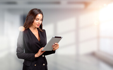 Attractive businesswoman wearing formal wear is holding tablet d