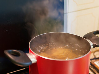 Closeup of boiling Fusilli which put salt and olive oil inside water in the pot on the gas stove. Easy homemade Italian food concept.