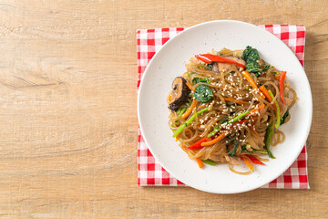 japchae or stir-fried Korean vermicelli noodles with vegetables and pork topped with white sesame