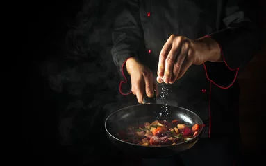 Photo sur Plexiglas Anti-reflet Manger Cooking fresh vegetables. The chef adds salt to a steaming hot pan. The idea of European cuisine for a hotel with advertising space.