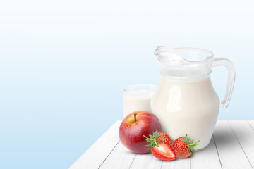 Glass of milk with apple and strawberry on wooden table with blue background.