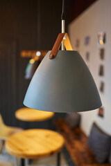 gray lamp on a loft-style leather strap in an empty coffee shop with round wooden tables