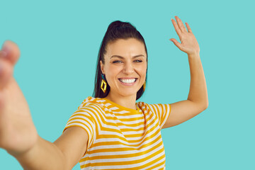 Fototapeta Joyful female blogger taking selfie or recording video for blog isolated on turquoise background. Close up of beautiful happy emotional european brunette woman taking first person selfie. Banner. obraz