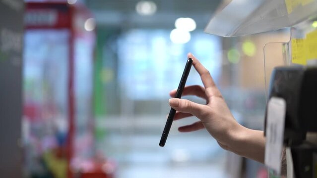 The cashier scans the screen of the smartphone. The cashier scans the QR code through a mobile payment service on the customer's smartphone in the store.