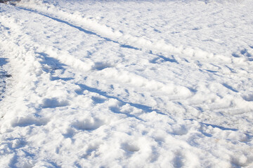 Fototapeta na wymiar Car tracks in the snow in sunlight