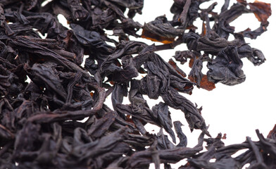 Dried black tea leaves on a white background.