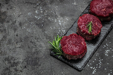 Beef medallions with rosemary and spices, Raw beef meat steak Tenderloin fillet on a dark...