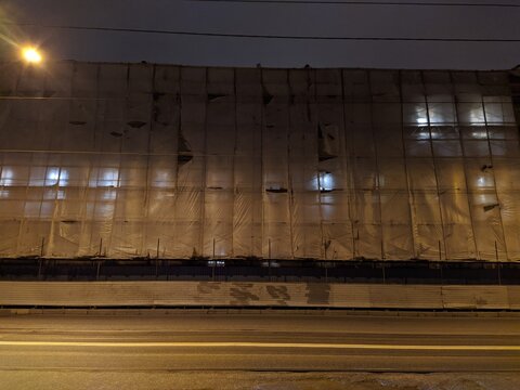multi storey building during renovation covered with fabric at night.