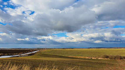 Fototapeta premium Sowing time in Ukraine during the war. Preparing fields for sowing grain. Blue sky, plowed land. terror.