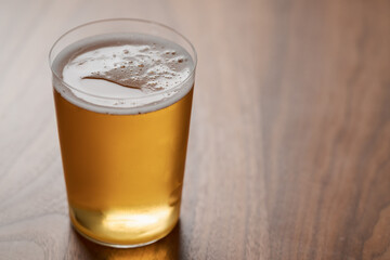 Apple cider in tumbler glass on walnut wood table with copy space