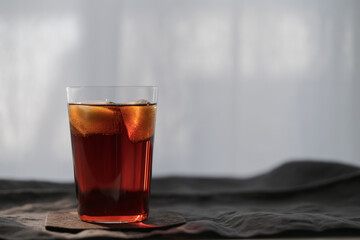 Cola with ice in tumbler glass on wood table with copy space