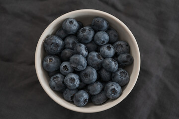 Fresh washed blueberris in white bowl on linen cloth