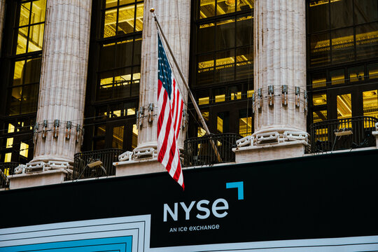 Columns over the entry of the illuminated building of New York Stock Exchange (NYSE) building on Wall Street with single American flag