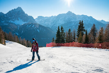 Fototapeta na wymiar Snowboarder standing on snowy mountain slope at winter resort on sunny day