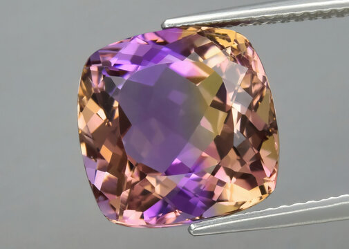 Natural gemstone colored ametrine in thongs on a gray background. Natural Bolivian bicolor yellow purple ametrine