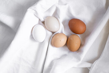 Multi-colored organic eggs from free range chickens on a rustic barn wood background. Multi-colored organic eggs from free range chickens on a rustic  background. A brown, white, egg in a row.