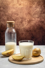vegan potato milk in glass and raw potato. Alternative plant based milk. superfood concept. Healthy, clean eating. Vegan or gluten free diet. vertical image place for text
