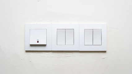 Front view of light and fan switch power electronic component and heater switch for air conditioner on white wall.