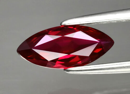 Natural precious red ruby in tongs on a gray background