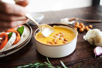 Pumpkin and chickpea cream. Someone introduces the spoon to eat. Mediterranean food.