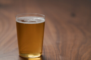 Apple cider in tumbler glass on walnut wood table with copy space