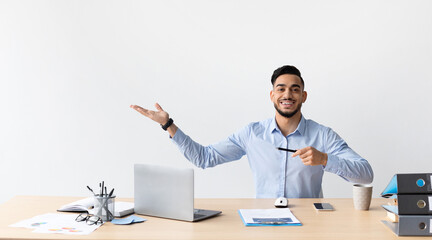 Happy Business Man Pointing Aside Sitting At Workplace