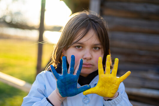 A child with the flag of Ukraine. Sadness longing hope. Children's sadness from the war. Evacuation of civilians. Freedom to Ukraine.
Hands painted in Ukraine flag