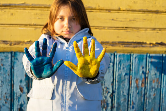 A child with the flag of Ukraine. Sadness longing hope. Children's sadness from the war. Evacuation of civilians. Freedom to Ukraine.
Hands painted in Ukraine flag