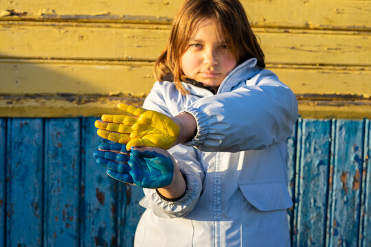 A child with the flag of Ukraine. Sadness longing hope. Children's sadness from the war. Evacuation of civilians. Freedom to Ukraine.
Hands painted in Ukraine flag