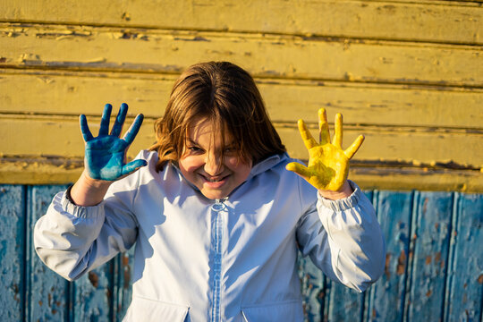 A child with the flag of Ukraine. Sadness longing hope. Children's sadness from the war. Evacuation of civilians. Freedom to Ukraine.
Hands painted in Ukraine flag