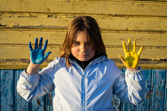 A child with the flag of Ukraine. Sadness longing hope. Children's sadness from the war. Evacuation of civilians. Freedom to Ukraine.
Hands painted in Ukraine flag
