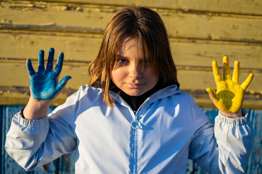 A child with the flag of Ukraine. Sadness longing hope. Children's sadness from the war. Evacuation of civilians. Freedom to Ukraine.
Hands painted in Ukraine flag