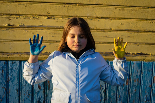 A child with the flag of Ukraine. Sadness longing hope. Children's sadness from the war. Evacuation of civilians. Freedom to Ukraine.
Hands painted in Ukraine flag