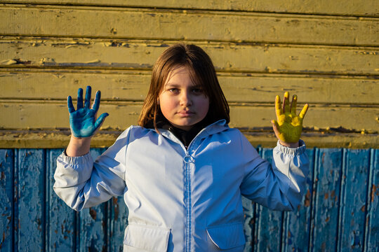 A child with the flag of Ukraine. Sadness longing hope. Children's sadness from the war. Evacuation of civilians. Freedom to Ukraine.
Hands painted in Ukraine flag