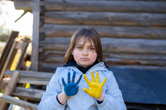 A child with the flag of Ukraine. Sadness longing hope. Children's sadness from the war. Evacuation of civilians. Freedom to Ukraine.
Hands painted in Ukraine flag