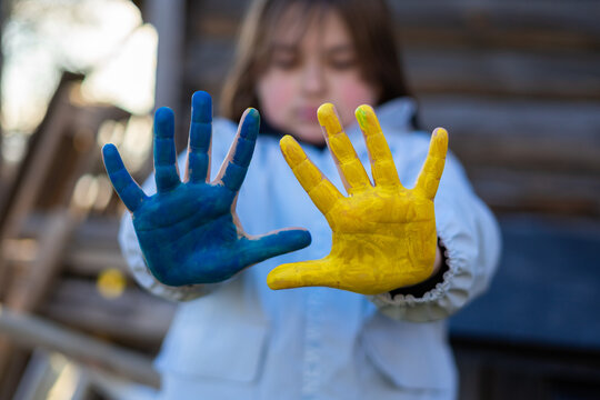 A child with the flag of Ukraine. Sadness longing hope. Children's sadness from the war. Evacuation of civilians. Freedom to Ukraine.
Hands painted in Ukraine flag