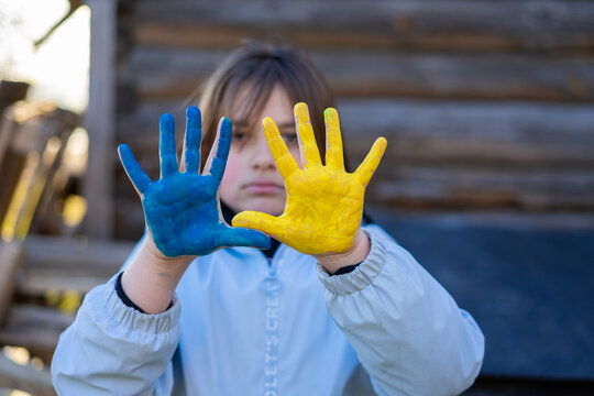 A child with the flag of Ukraine. Sadness longing hope. Children's sadness from the war. Evacuation of civilians. Freedom to Ukraine.
Hands painted in Ukraine flag