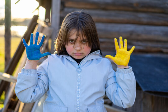 A child with the flag of Ukraine. Sadness longing hope. Children's sadness from the war. Evacuation of civilians. Freedom to Ukraine.
Hands painted in Ukraine flag