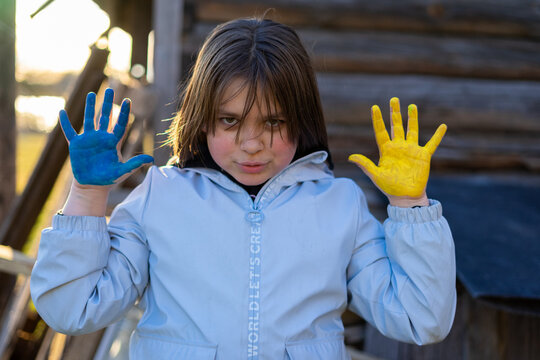 A child with the flag of Ukraine. Sadness longing hope. Children's sadness from the war. Evacuation of civilians. Freedom to Ukraine.
Hands painted in Ukraine flag