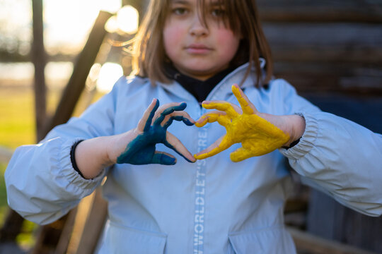 A child with the flag of Ukraine. Sadness longing hope. Children's sadness from the war. Evacuation of civilians. Freedom to Ukraine.
Hands painted in Ukraine flag