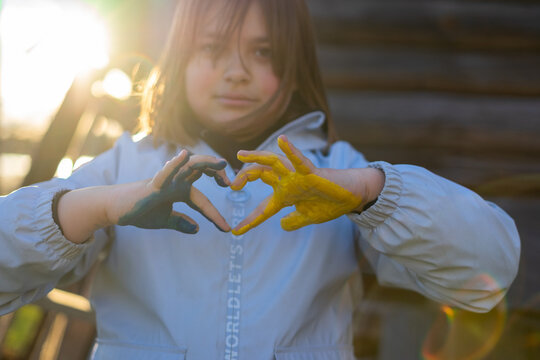 A child with the flag of Ukraine. Sadness longing hope. Children's sadness from the war. Evacuation of civilians. Freedom to Ukraine.
Hands painted in Ukraine flag