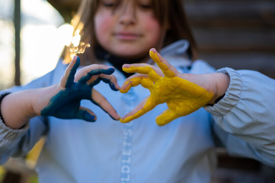 A child with the flag of Ukraine. Sadness longing hope. Children's sadness from the war. Evacuation of civilians. Freedom to Ukraine.
Hands painted in Ukraine flag
