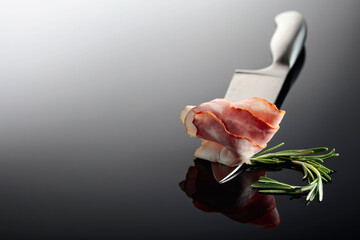 Bacon with rosemary on a kitchen knife.