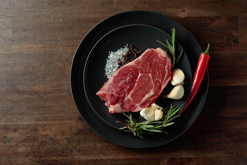 Raw beef steak with rosemary, garlic, salt, and pepper.