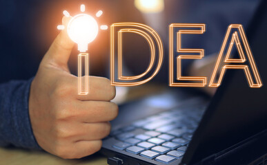 A man is working on a laptop and thumbs up next to an orange light bulb indicating that a new idea or idea is emerging. creative and innovation development or problem solving concepts.