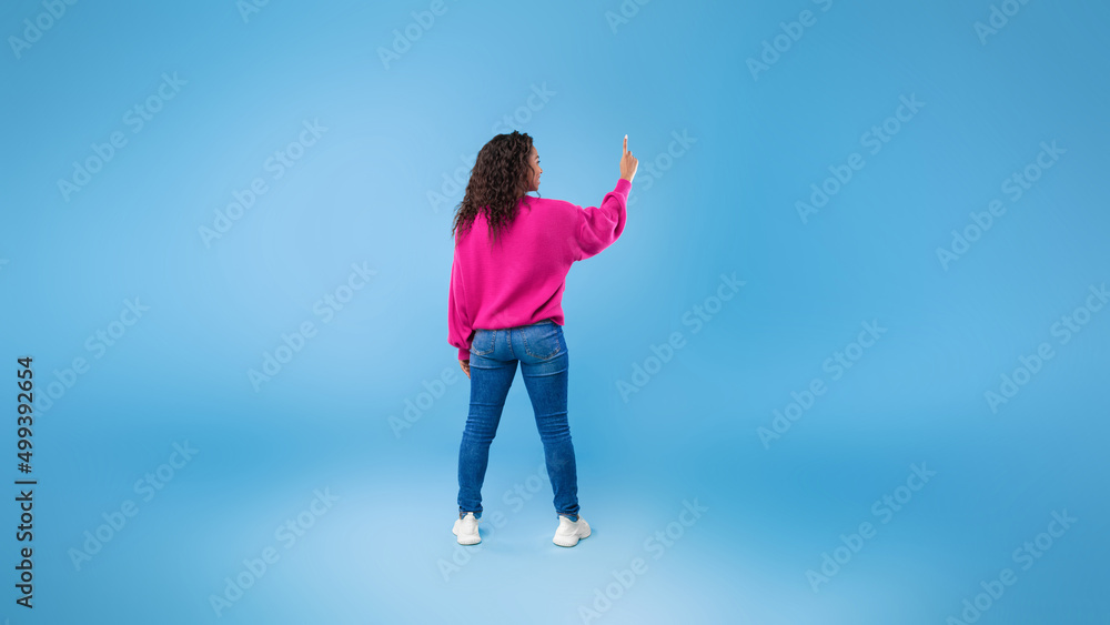 Poster back view of millennial african american lady touching imaginary screen, pressing button, using virt