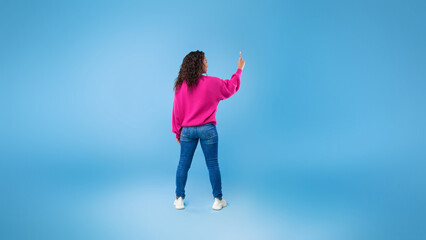 Back view of millennial African American lady touching imaginary screen, pressing button, using...